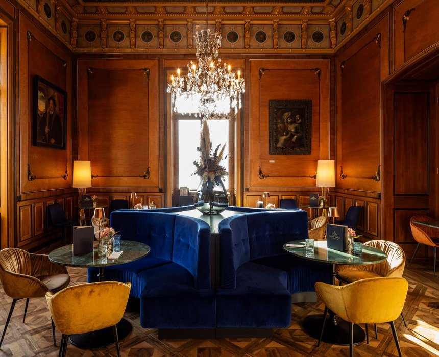 Historischer Salon von Schloss Montfort mit blauen Sofas, edlen Leuchten und einer eleganten Dekoration.