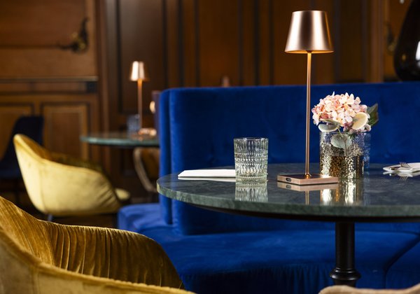 Tischdekoration mit Blumen und Kupferleuchte auf einem runden Tisch im eleganten Ambiente von Schloss Montfort.