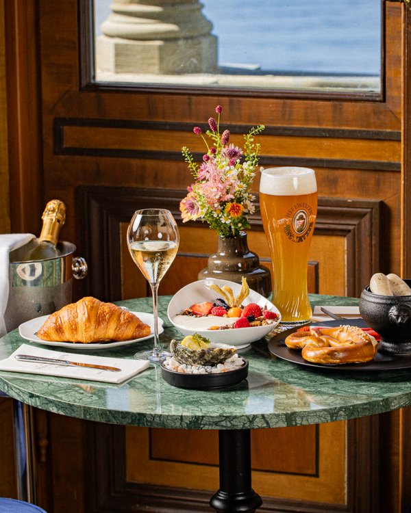 Frühstückstisch mit Champagner, Croissant, Bier und frischen Brezeln mit Seeblick