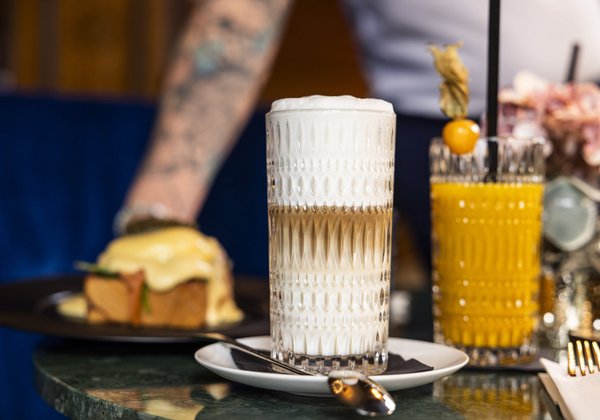 Ein Latte Macchiato und ein frischer Saft auf einem Tisch im Schloss Montfort, bereit zum Genießen.